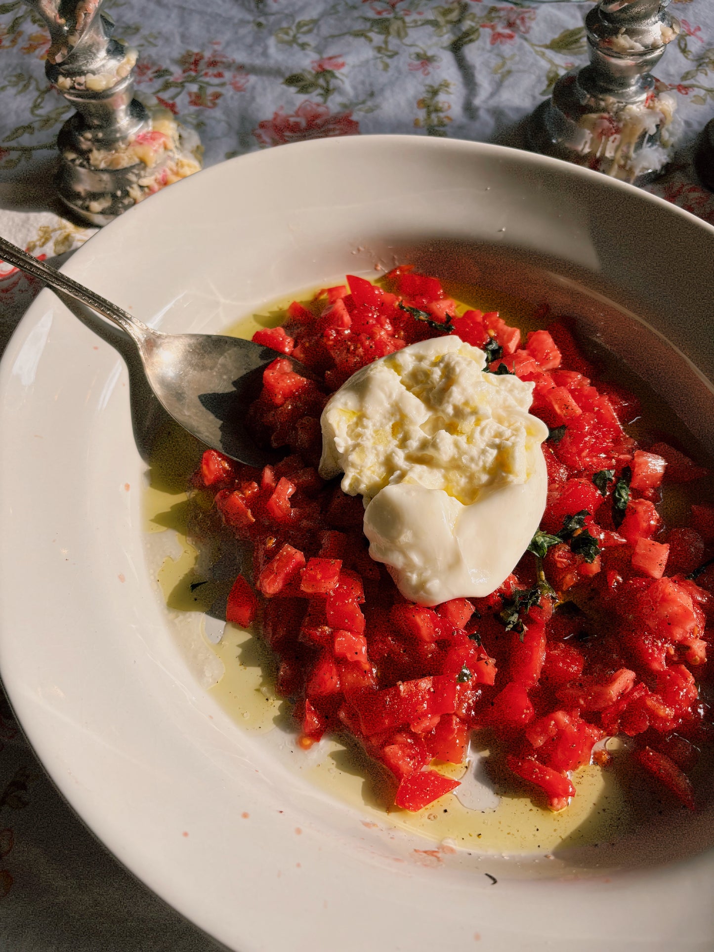 Plated dish with red vegetable salad and a dollop of white sauce on a floral tablecloth.